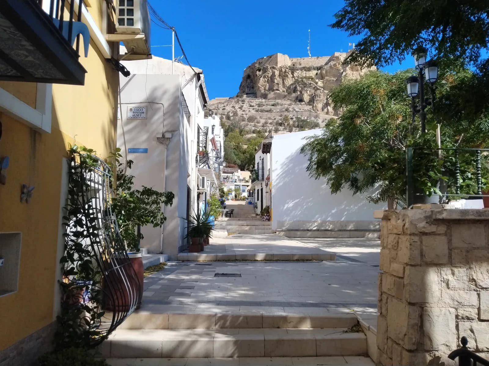 Calle con escaleras del barrio de Santa Cruz, en el casco antiguo de Alicante, con el castillo al fondo