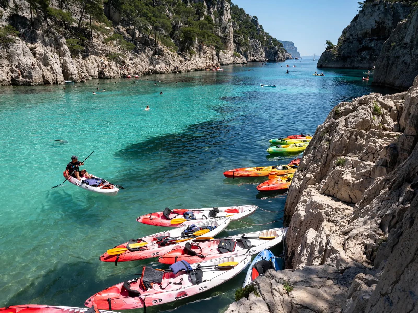 Kayaks junto a los acantilados de una cala mediterránea de aguas turquesas