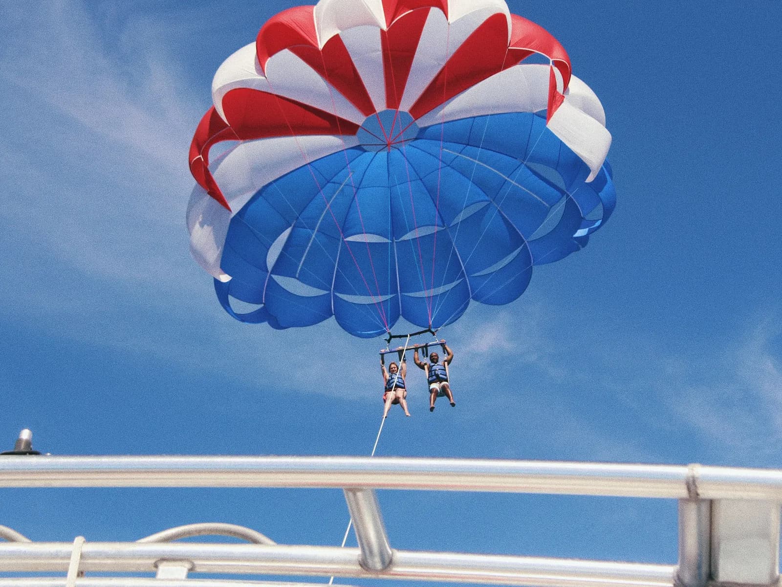 Dos personas volando en parasailing vistas desde la lancha