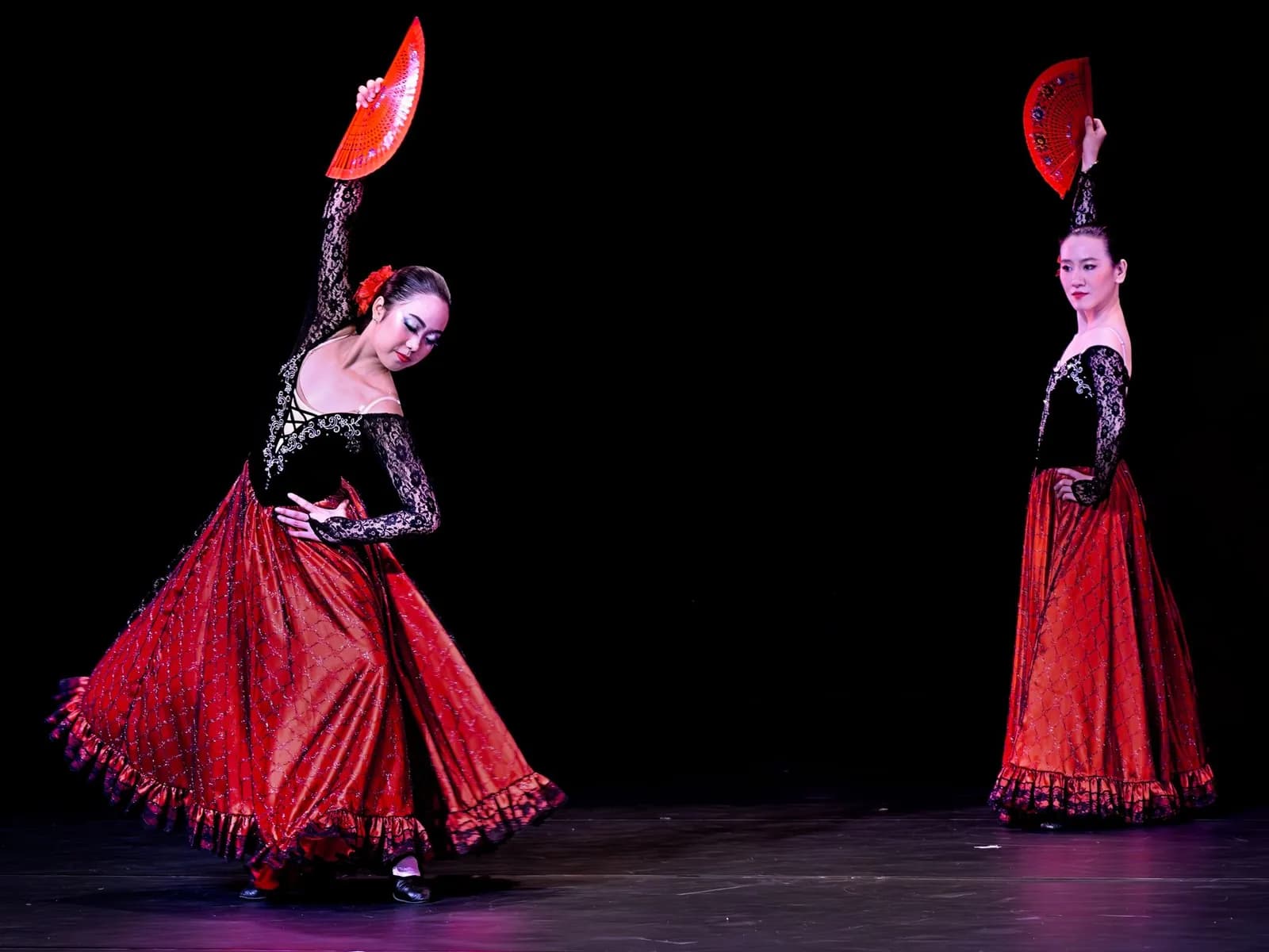 Flamenco dancers in red and black dresses on stage
