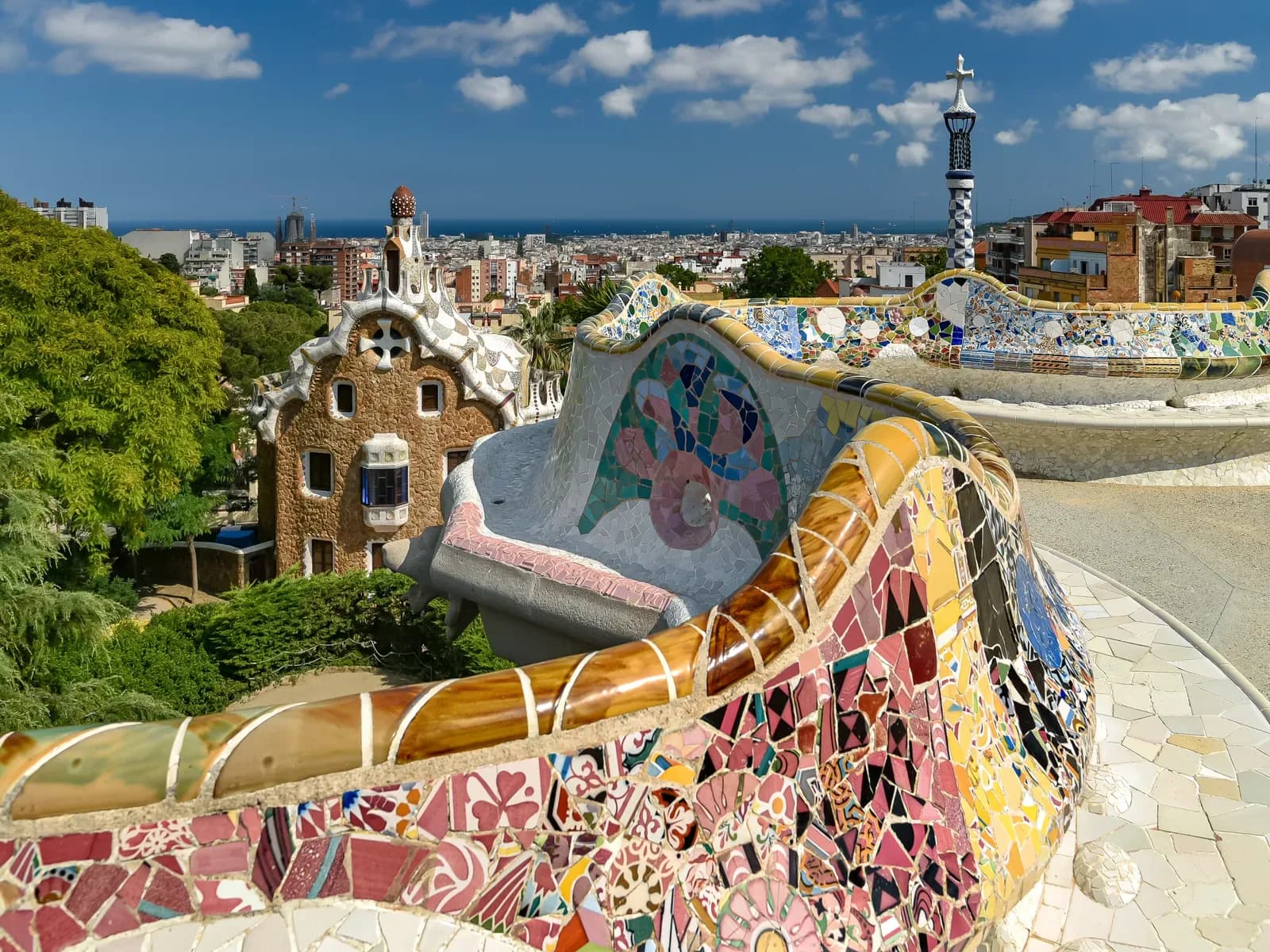 Terrace with Park Guell's wavy mosaic bench and views of Barcelona and the sea in the background