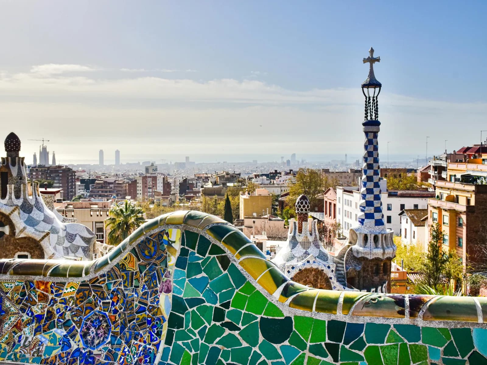 Banco de trencadís del Park Güell con la torre del pabellón y vistas a Barcelona y al mar