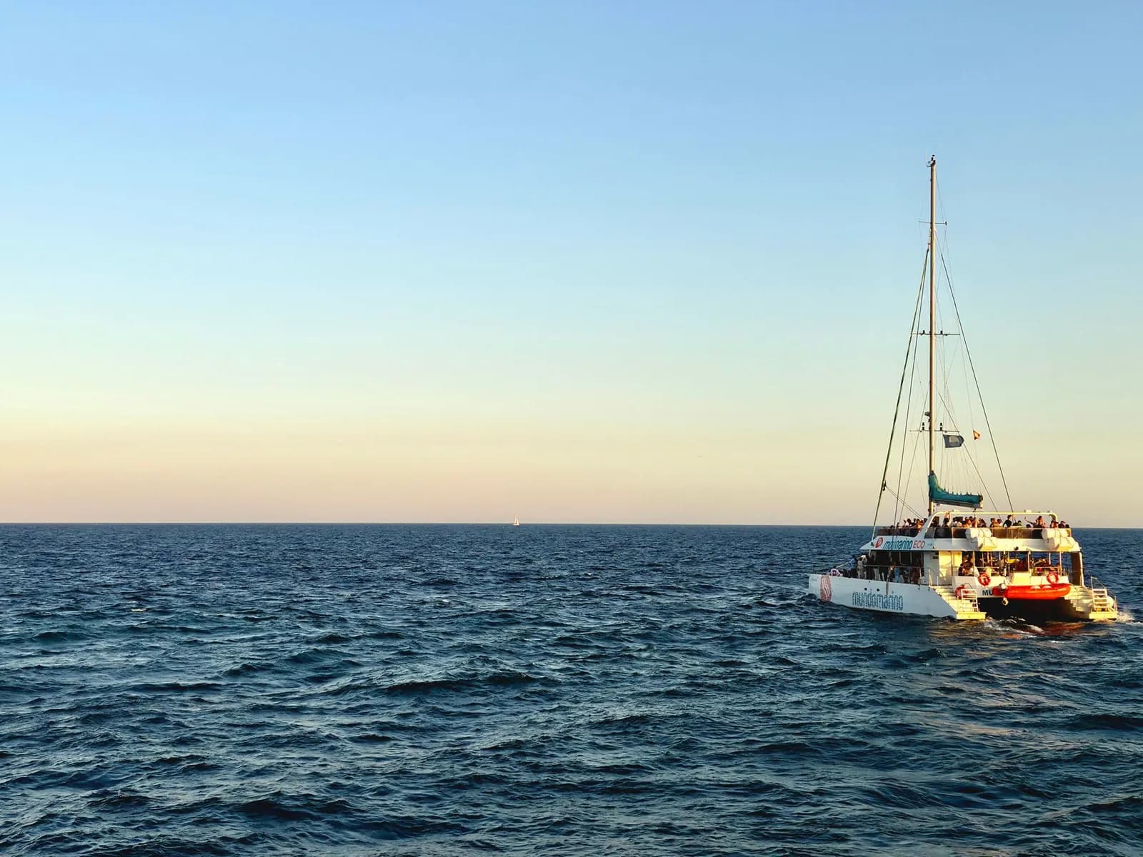 Catamarán de vela navegando al atardecer