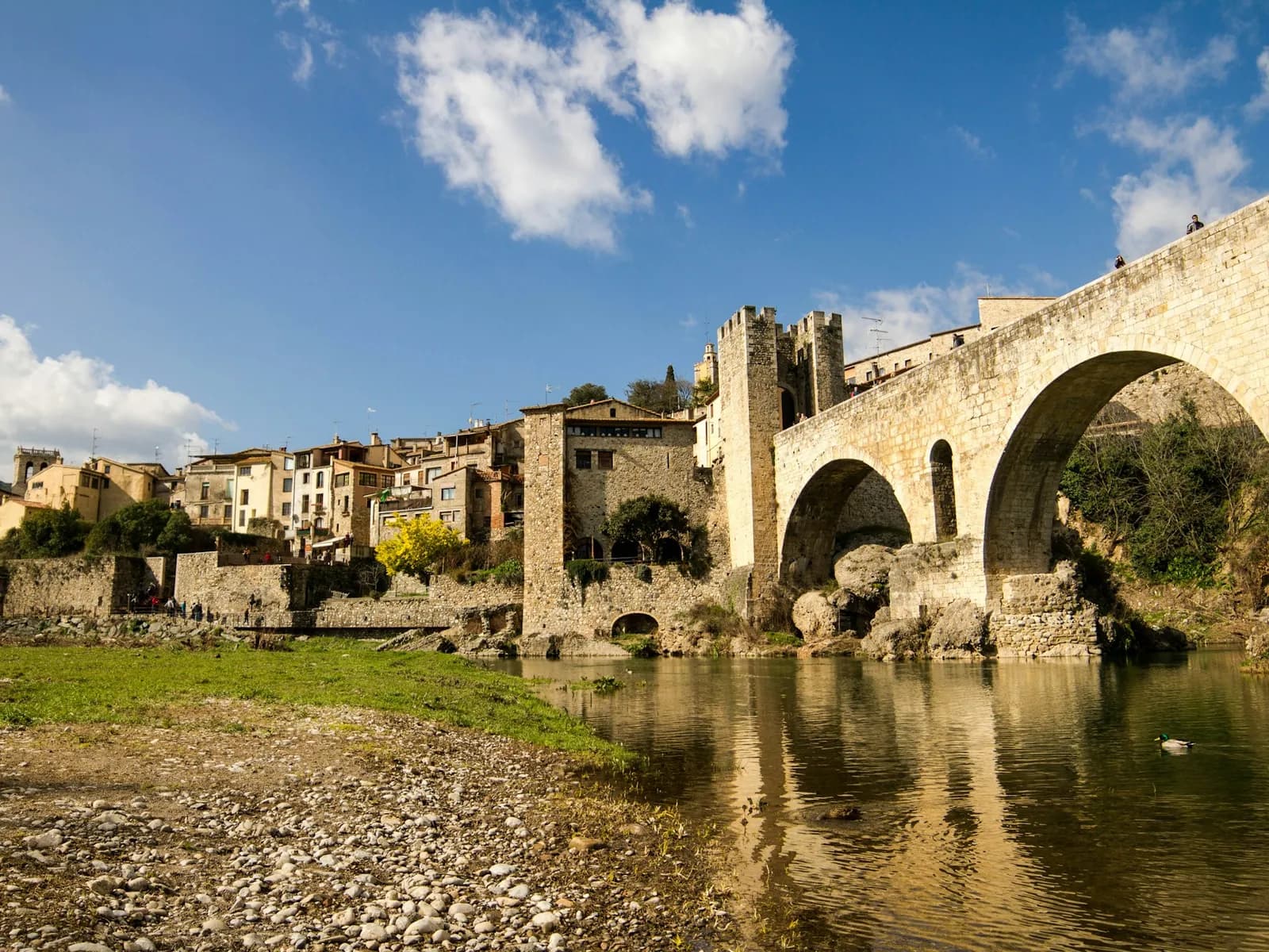 Arches of the medieval Besalú bridge with the village behind