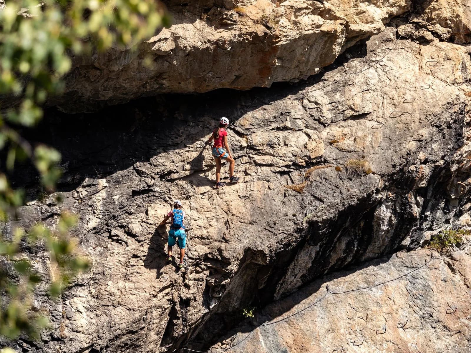 Two people climbing a via ferrata on a rock face