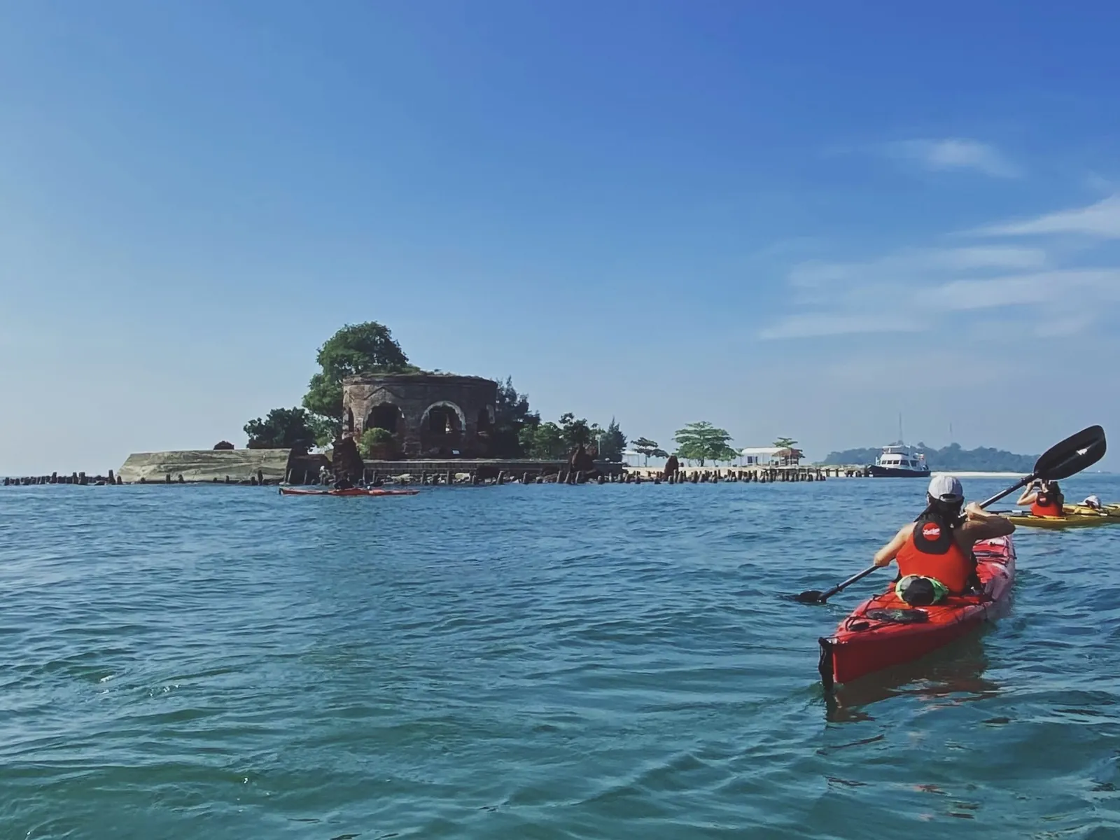 Kayak rojo navegando junto a un islote en aguas transparentes