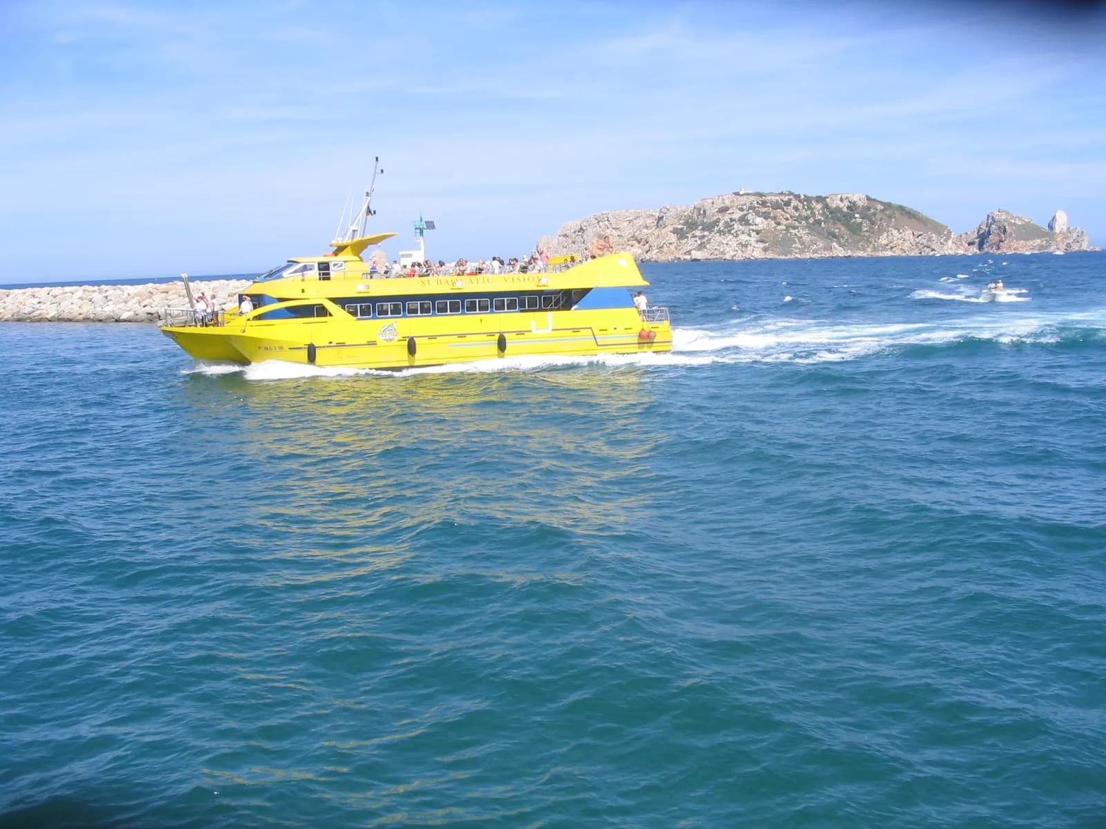 Barco amarillo de excursión saliendo de L'Estartit con las islas Medes al fondo