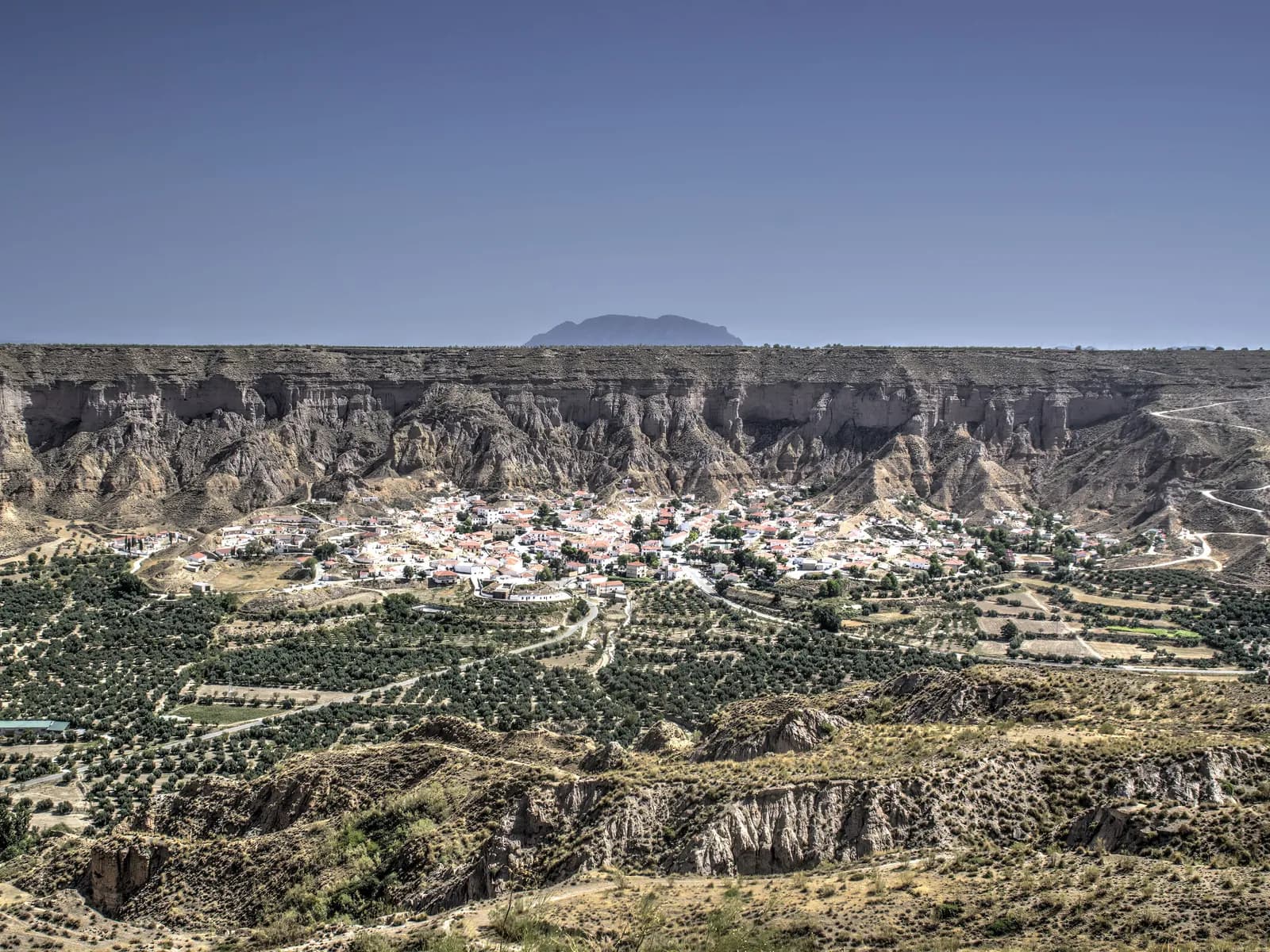 Cañón de Gorafe con sus paredes de badlands y el pueblo en el fondo del valle, entre olivos