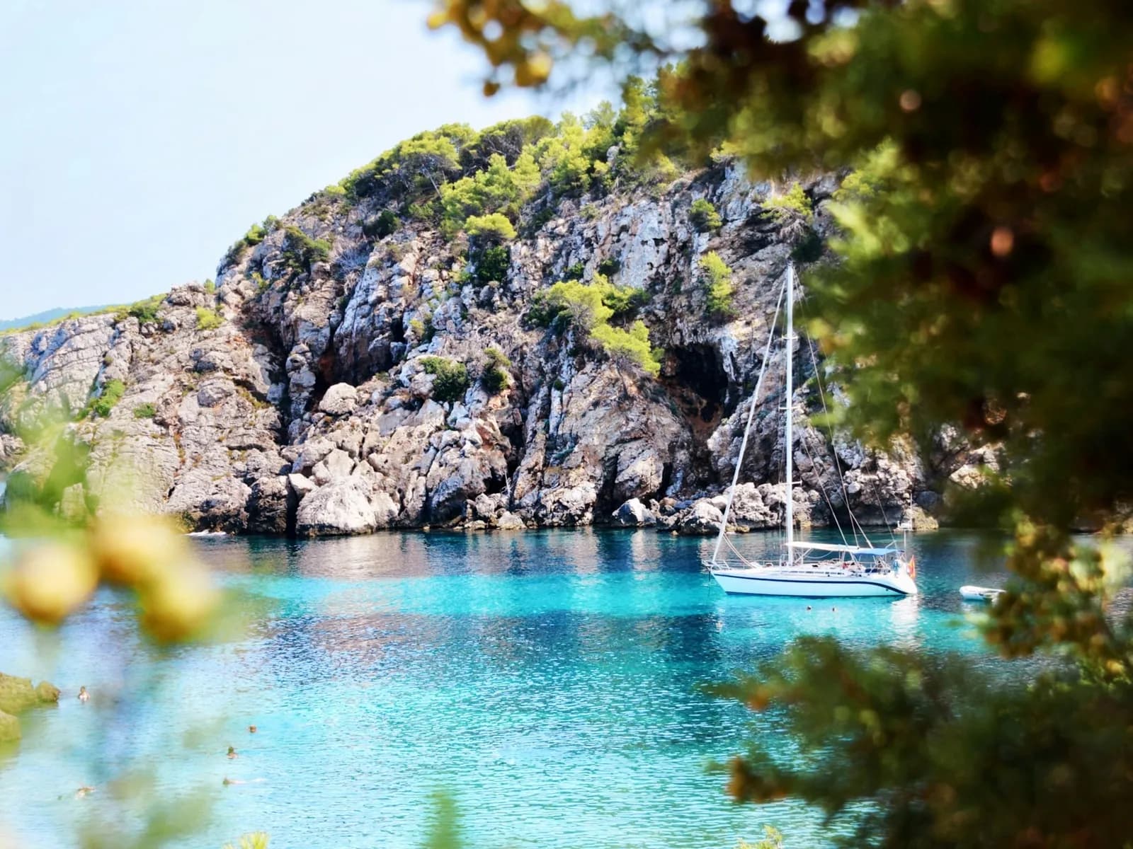 Boat anchored in a turquoise cove between cliffs