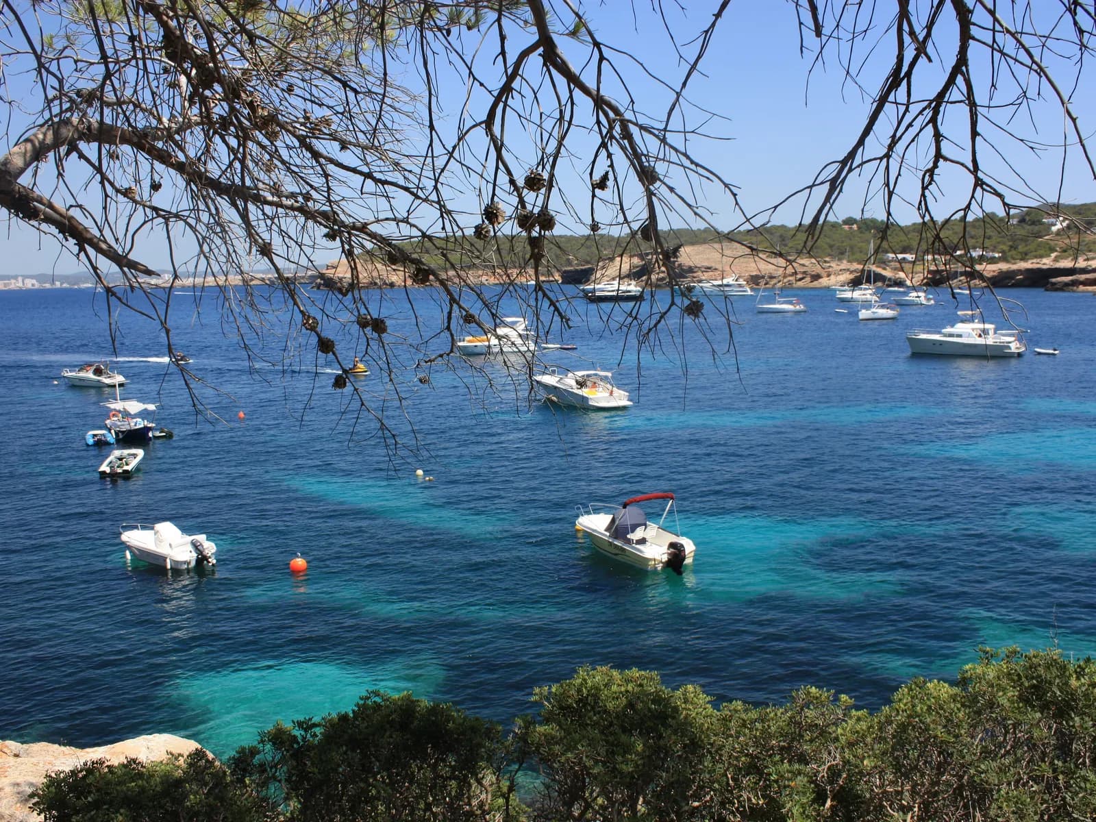 Boats anchored in the turquoise water of Cala Bassa