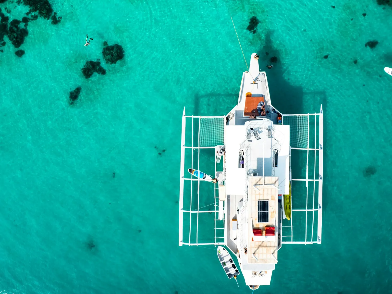 Catamaran anchored in turquoise water, seen from above