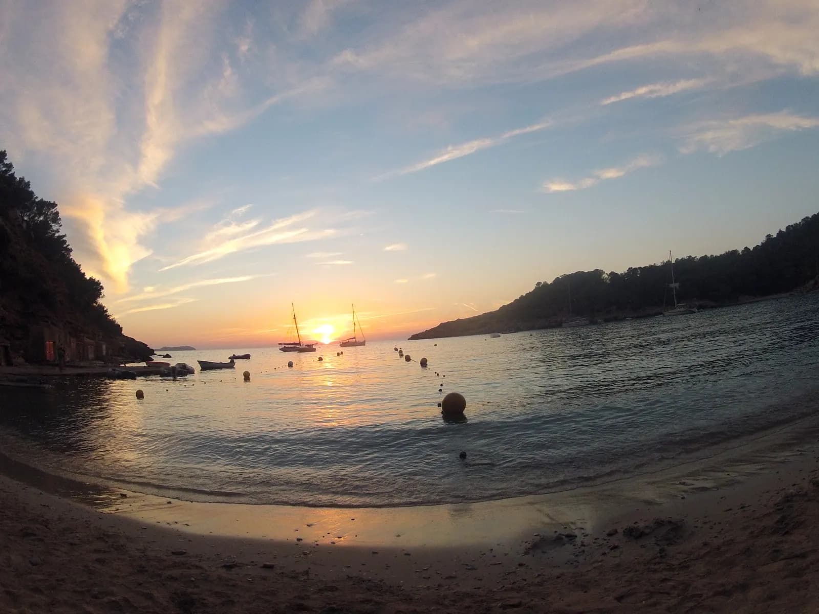 Puesta de sol en Cala Salada con veleros fondeados en la bahía