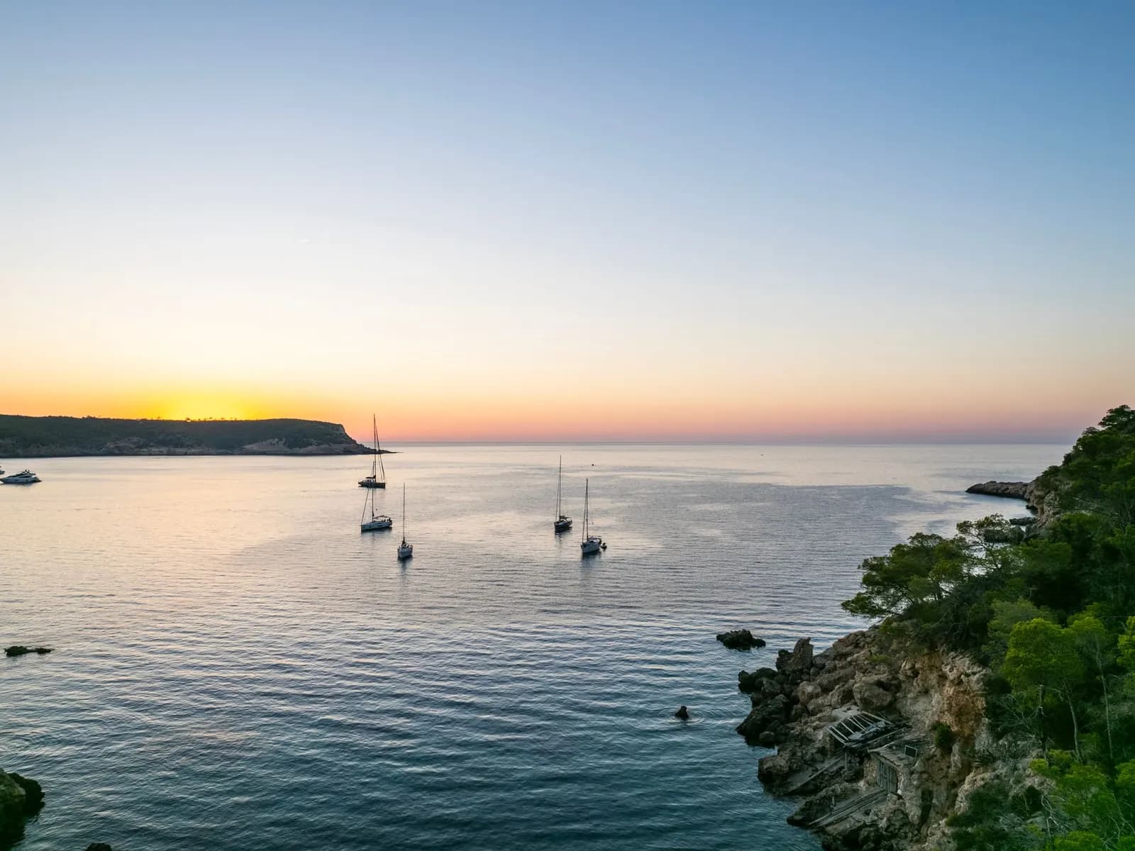 Boats anchored in an Ibiza cove at sunset