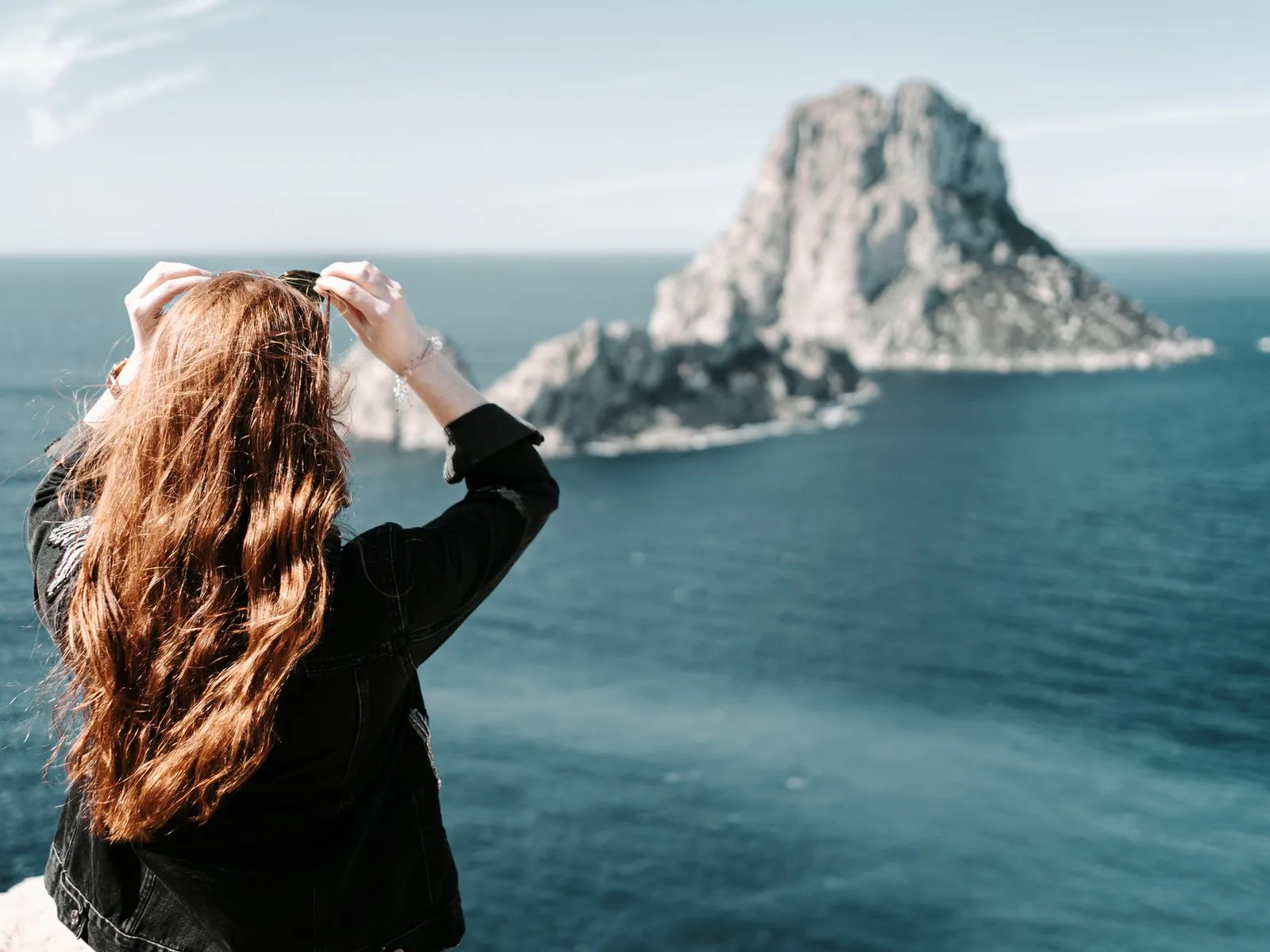 Traveller, seen from behind, photographing Es Vedrà from a viewpoint