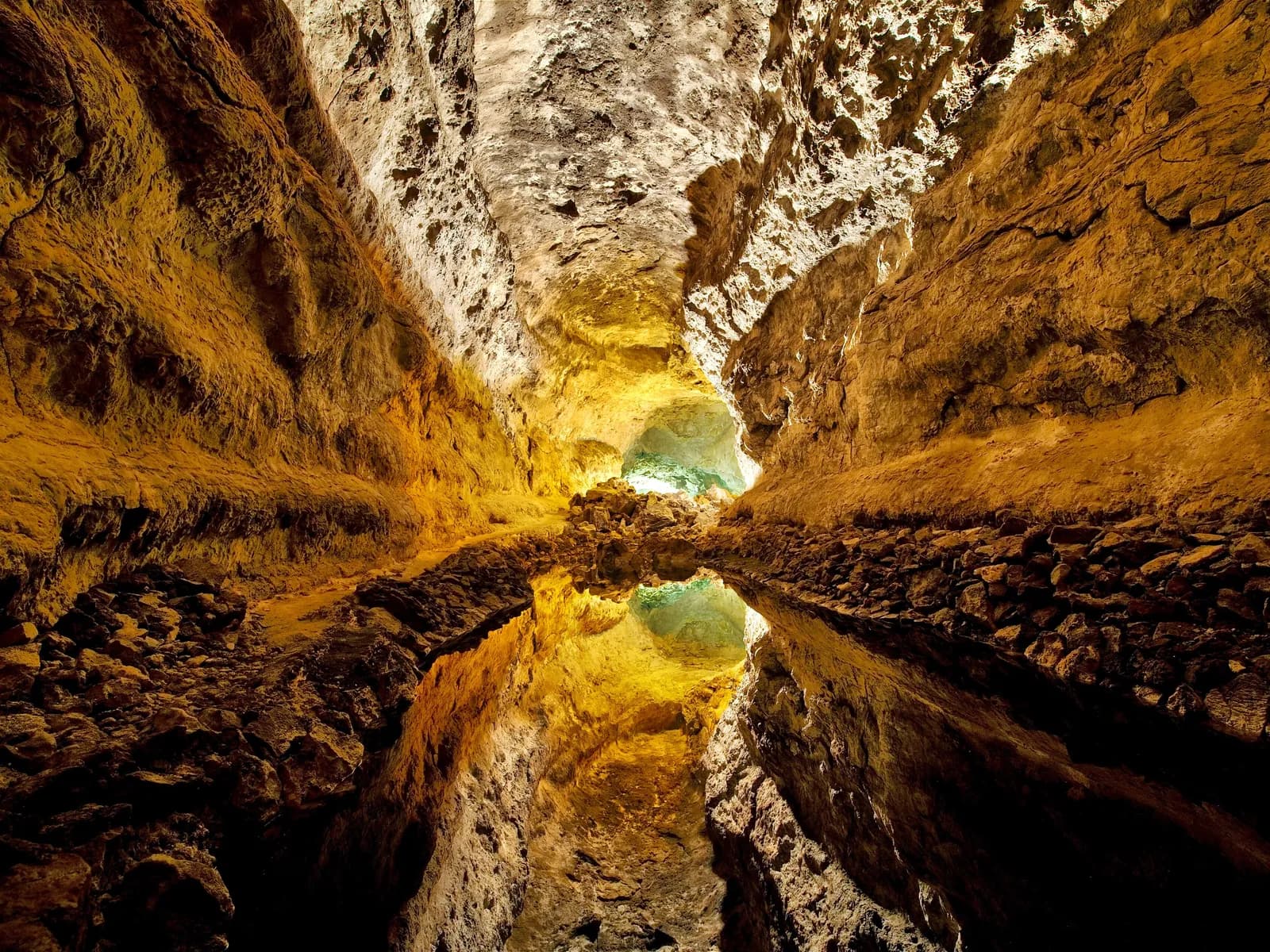 Galería iluminada de la Cueva de los Verdes reflejada en el agua