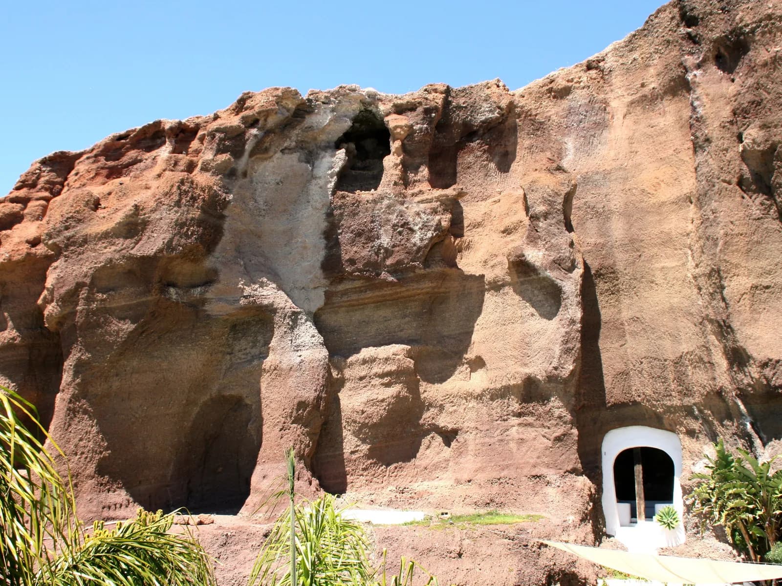Pared de roca con cuevas y puerta blanca en LagOmar