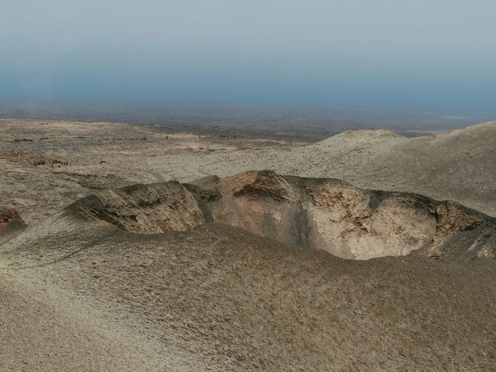 Cráter volcánico entre campos de lava en Lanzarote