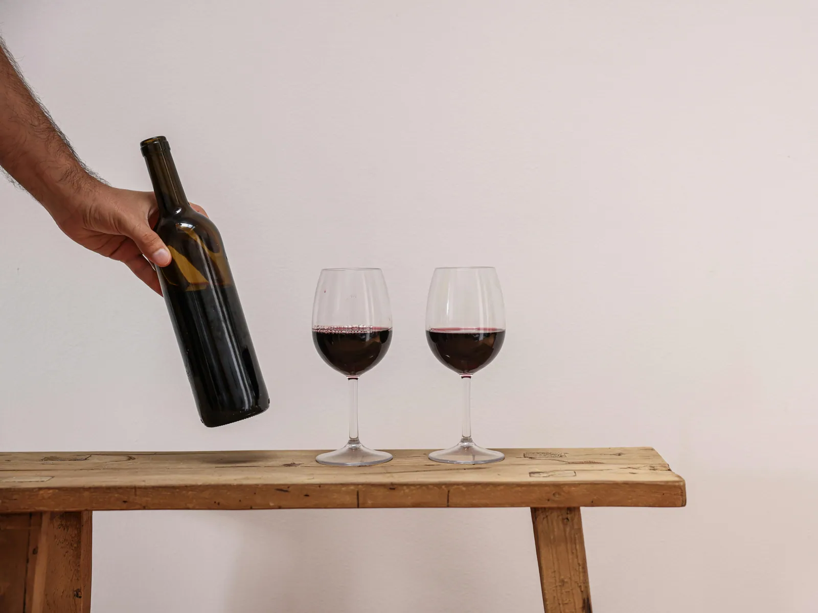 A bottle of red wine and two filled glasses