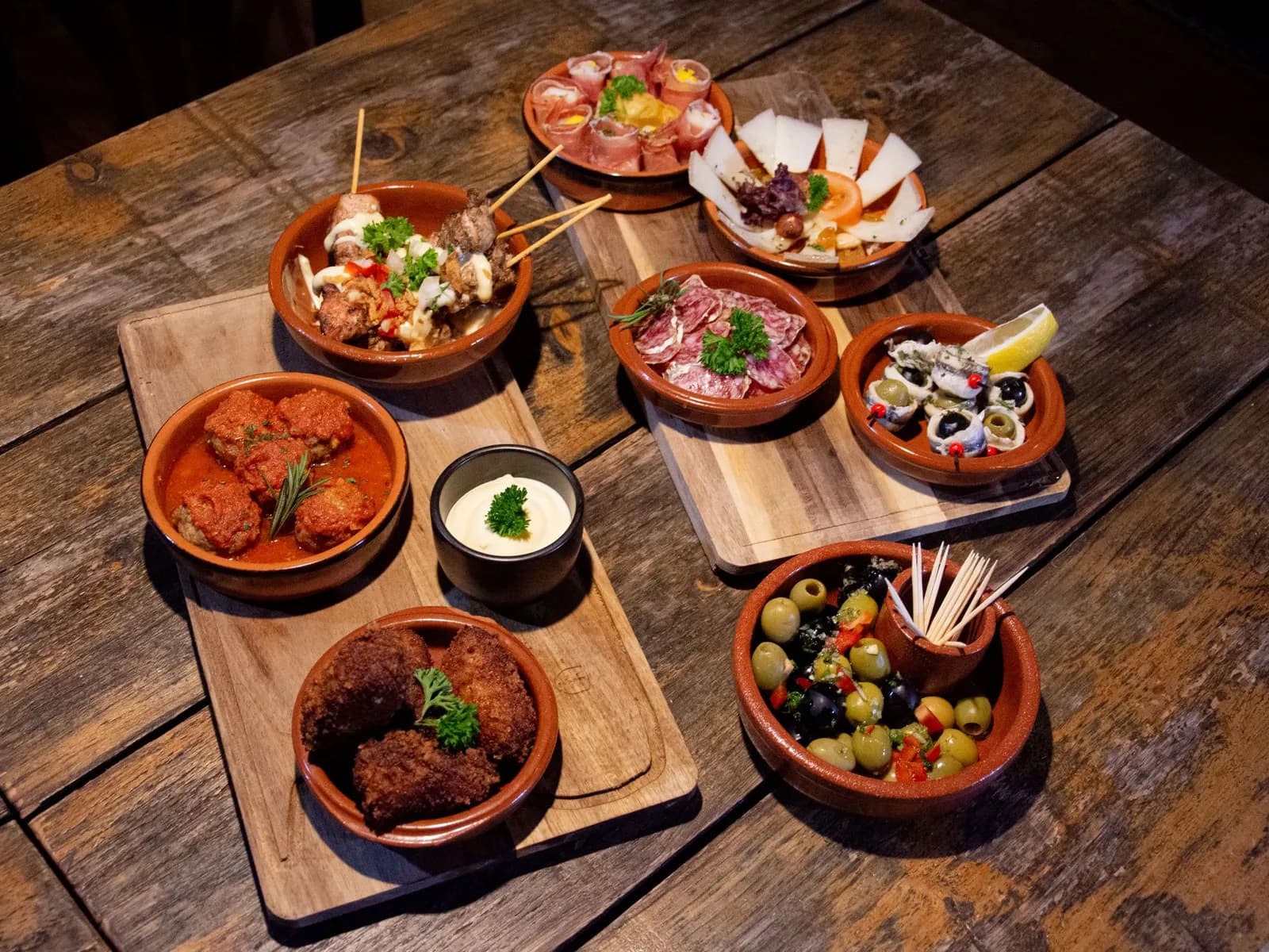 Tapas variadas en cazuelas de barro sobre una mesa de madera