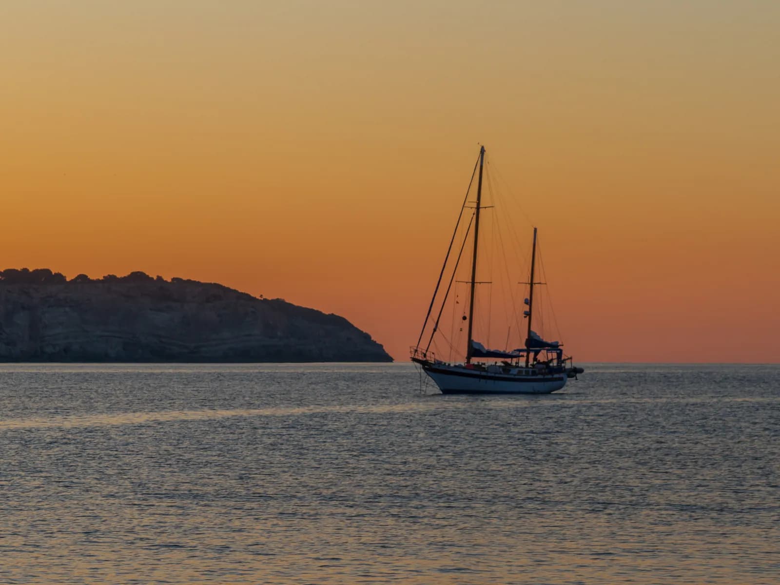 Velero navegando al atardecer frente a la costa de Mallorca