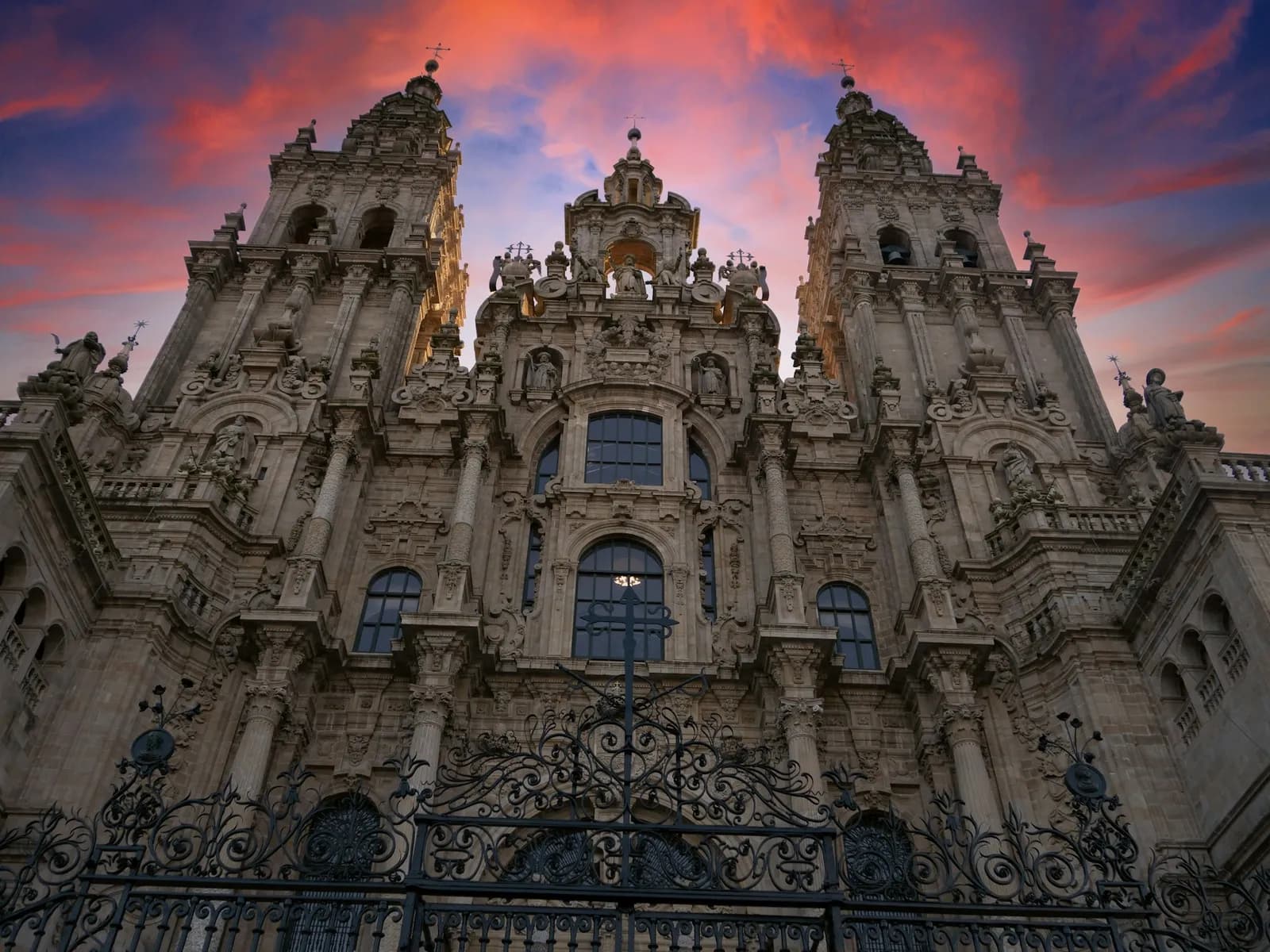 Obradoiro façade at nightfall under a reddish sky