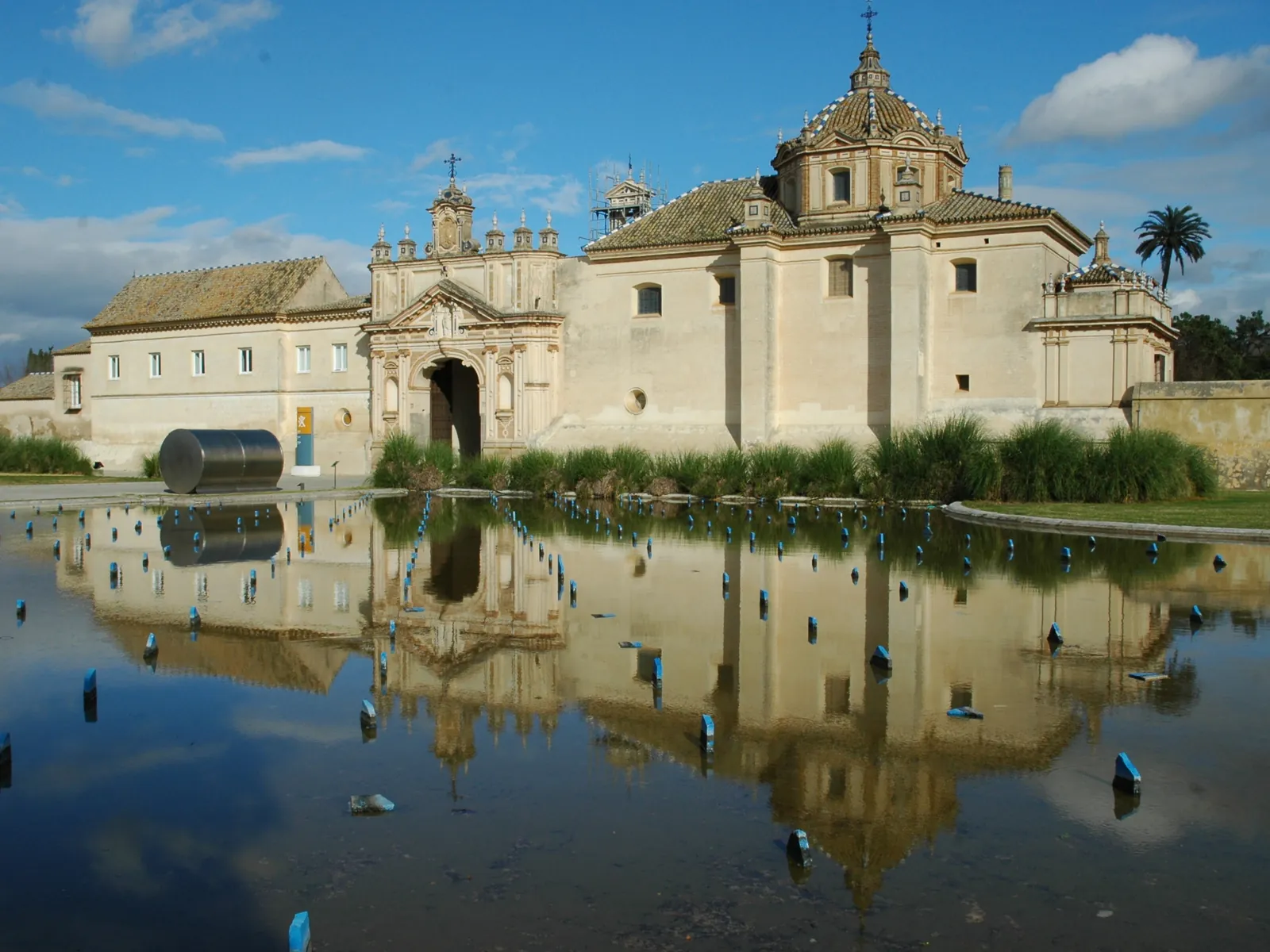 Monasterio de la Cartuja de Sevilla reflejado en el estanque bajo un cielo azul