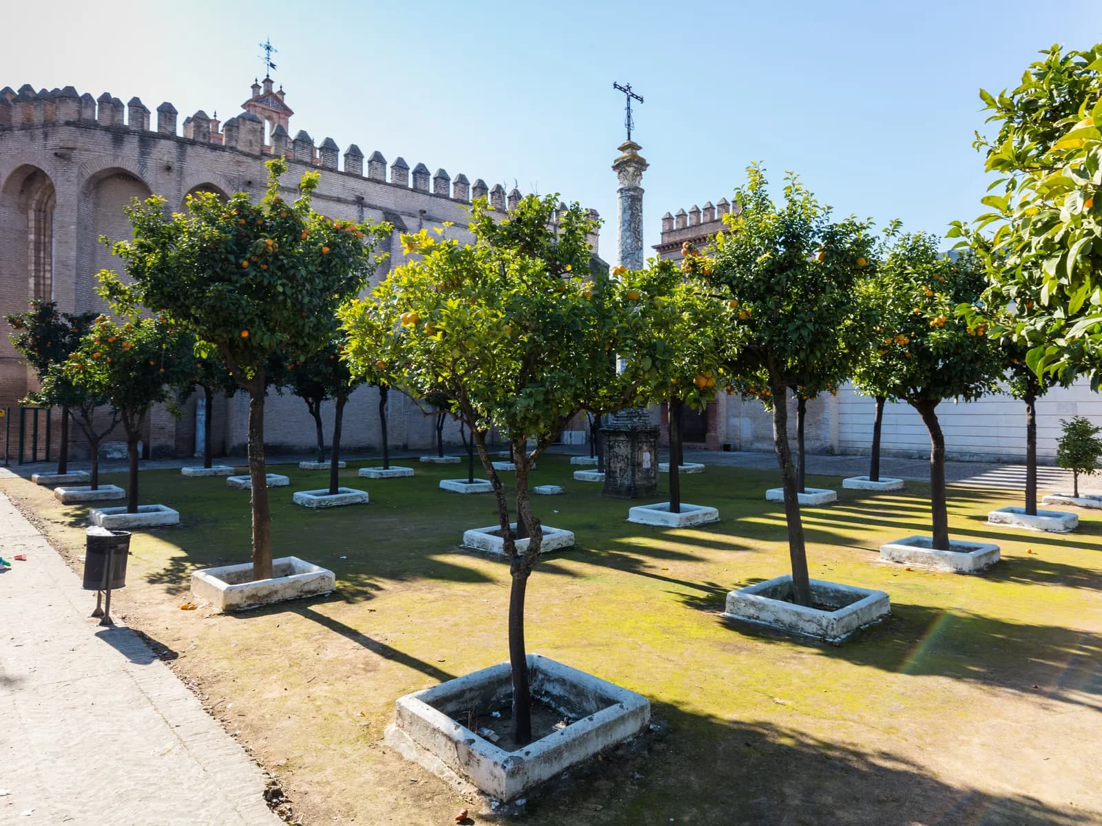 Muros almenados del Monasterio de San Isidoro del Campo con naranjos en primer plano