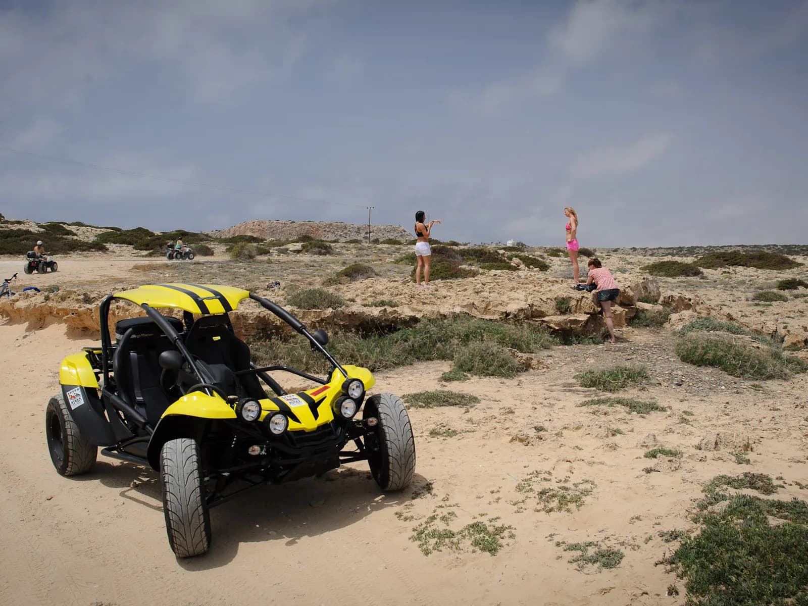 Buggy amarillo aparcado en un terreno de arena y matorral