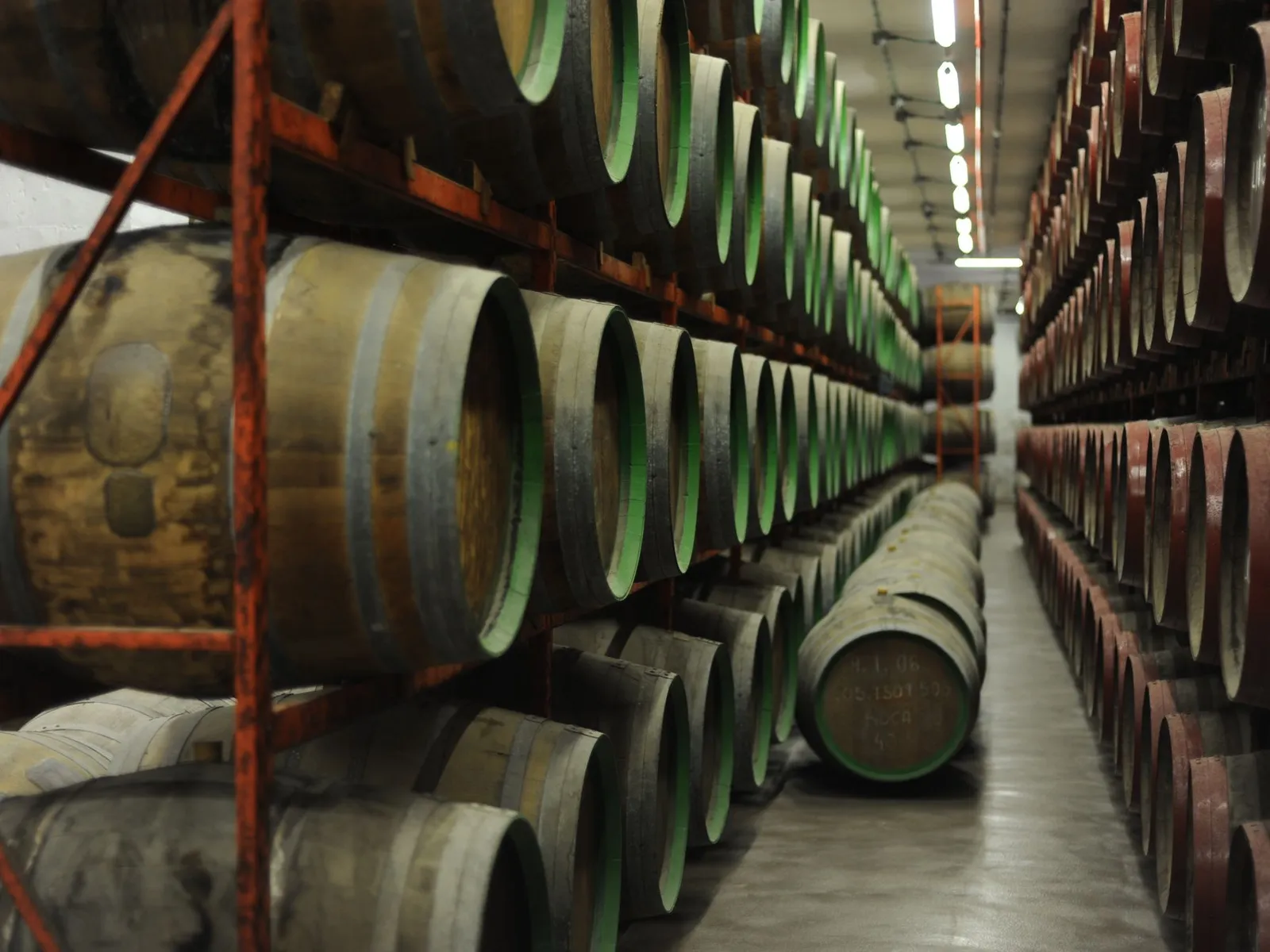 Winery aisle lined with stacked wine barrels