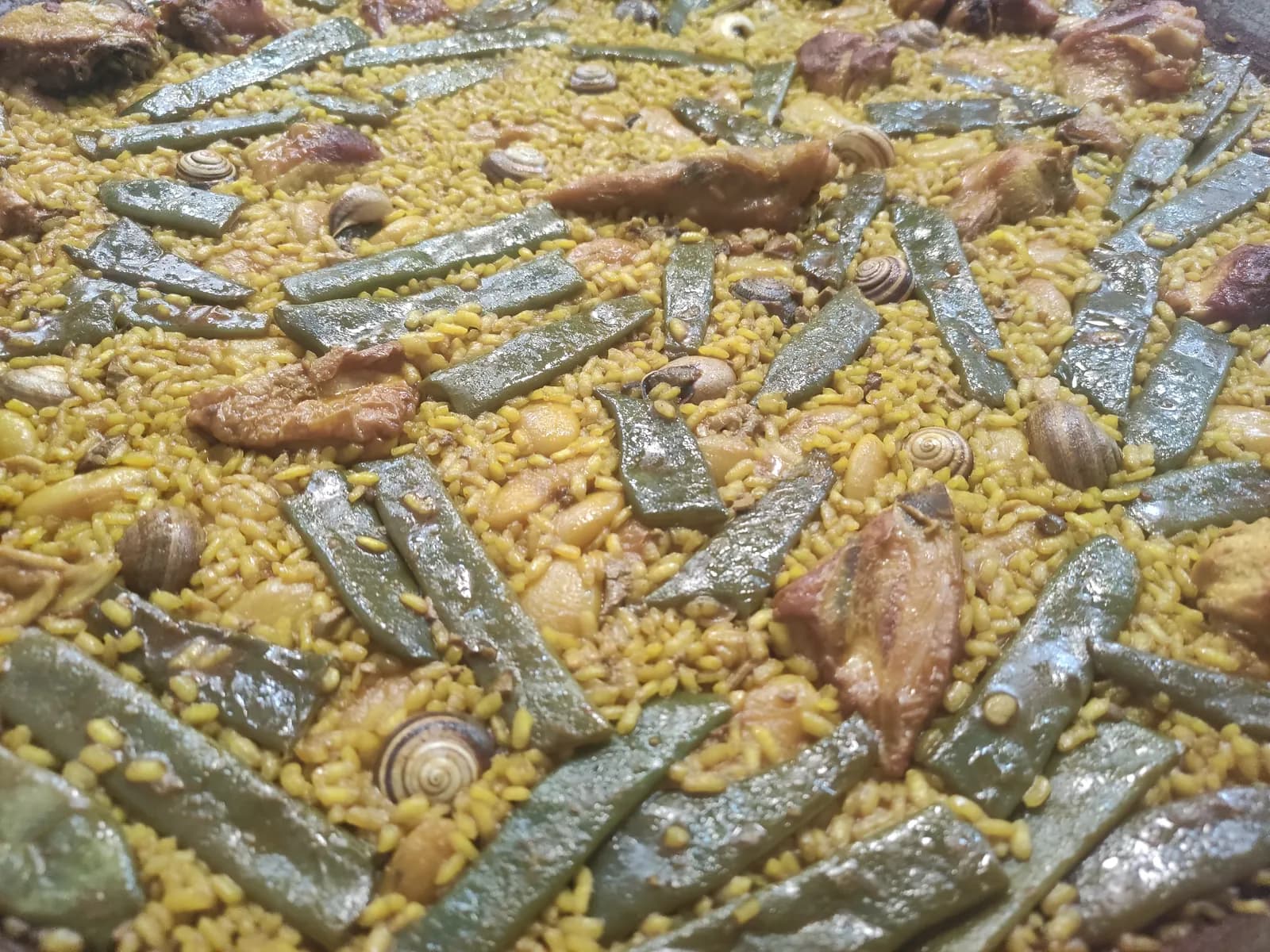 Paella valenciana con pollo, judía verde y caracoles en un restaurante de Valencia