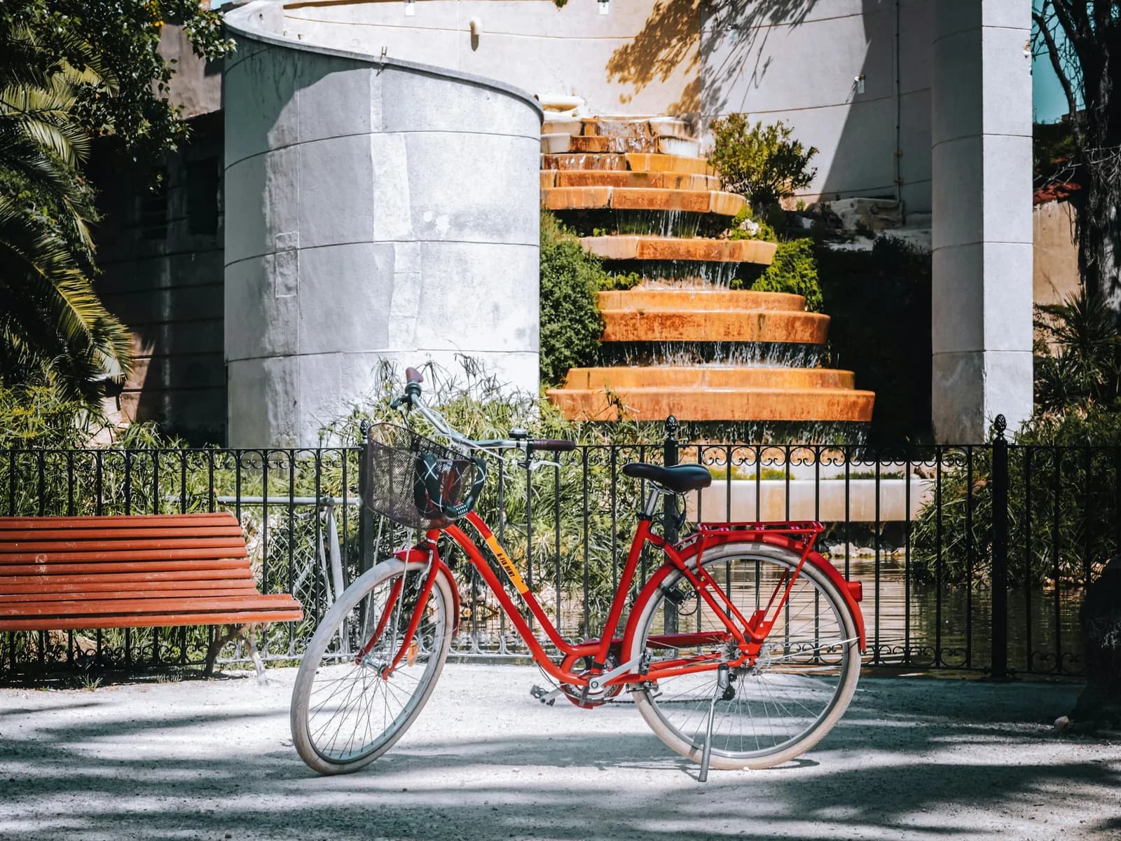 Bicicleta roja aparcada junto a un banco en Valencia