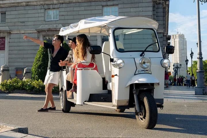 Tuk-tuk turístico frente a un monumento icónico de Madrid