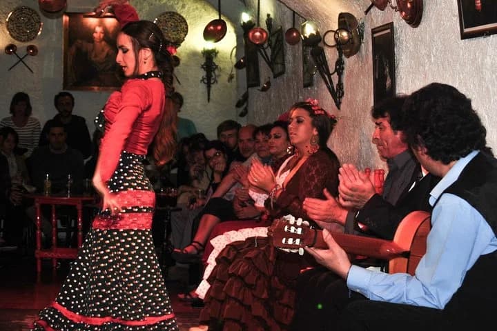 Flamenco dancer in a red dress beside the guitarist in a tablao