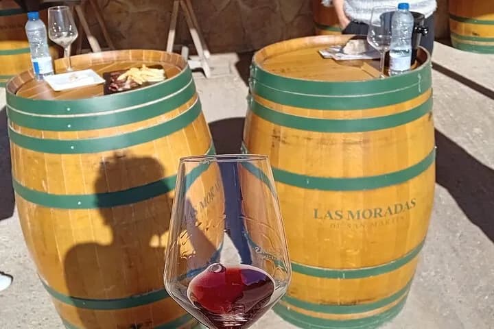 Copa de vino tinto sobre barricas en una bodega