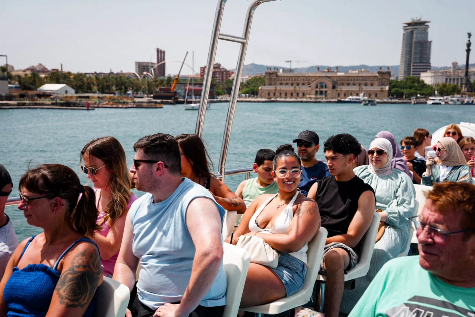 Viajeros en la cubierta de un barco frente al puerto de Barcelona
