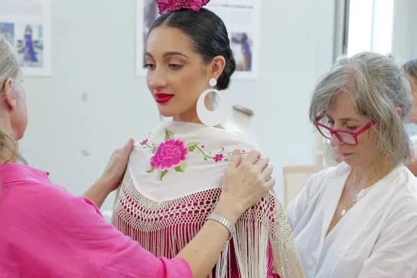 Modista ajustando un traje de flamenca a una clienta en el taller
