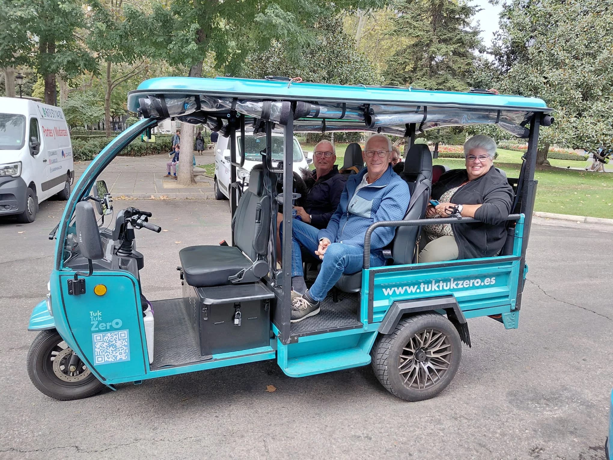 Pasajeros en un tuk-tuk eléctrico turquesa por Madrid