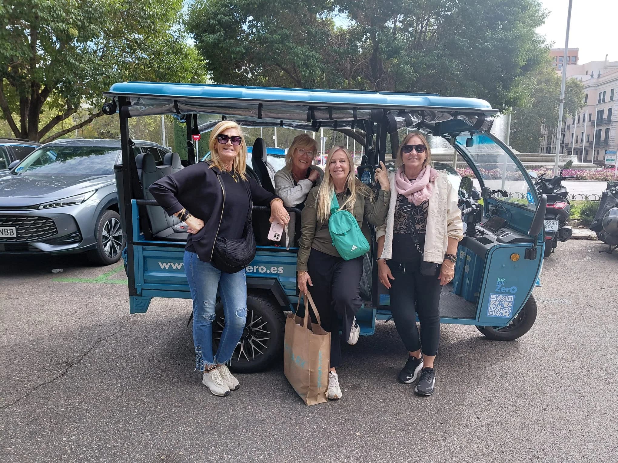 Grupo de viajeras junto a un tuk-tuk eléctrico en Madrid