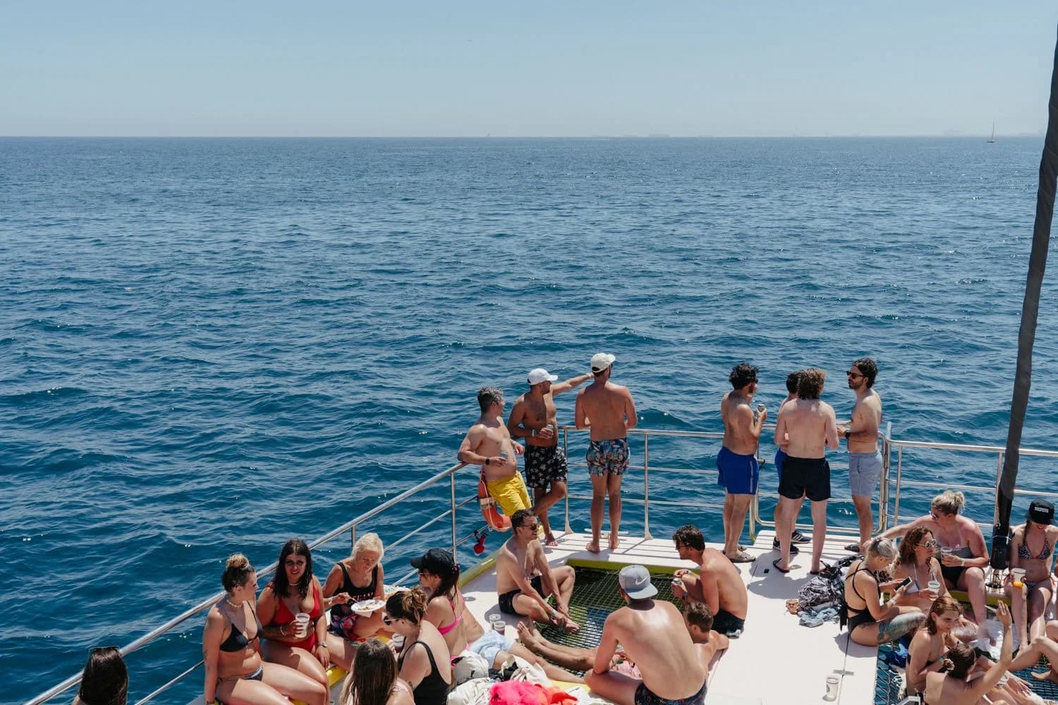 Catamarán lleno de gente navegando frente a Barcelona