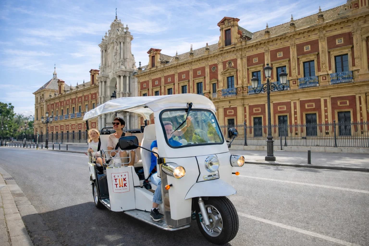 Tuk tuk eléctrico con pasajeros frente al Palacio de San Telmo